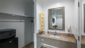 A bathroom with a granite countertop, a sink, a mirror, and a shower area. - Motel 6 Norwalk, CA (Norwalk)