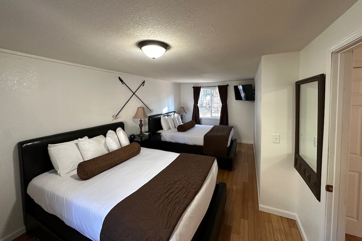 Habitación de hotel con dos camas, una lámpara en el techo, televisión y ventana con cortinas.