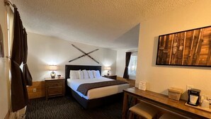 A hotel room with a bed, bedside tables, a desk, and a chair.