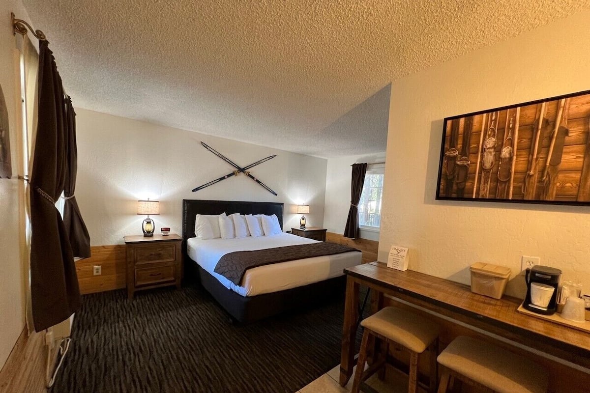 Una habitación de hotel con cama, mesitas de noche, escritorio y silla.