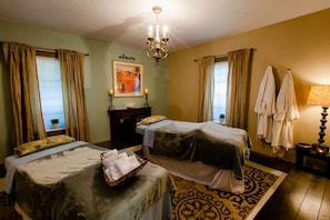 A hotel room with two beds, a chandelier, a painting, and a patterned rug.