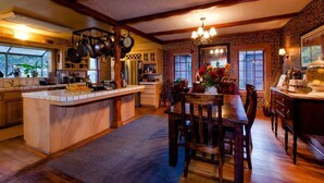 A spacious kitchen with a central island, wooden cabinets, and a dining area with a table and chairs. - Strawberry Valley Inn (Mount Shasta)