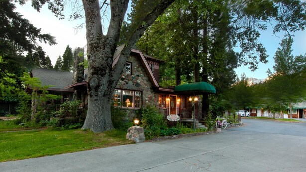 A stone house with a porch and a green awning, surrounded by trees and a clear sky. - Strawberry Valley Inn (Mount Shasta)