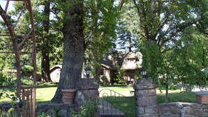 A stone gate leading to a house with a large tree in the foreground. - Strawberry Valley Inn (Mount Shasta)