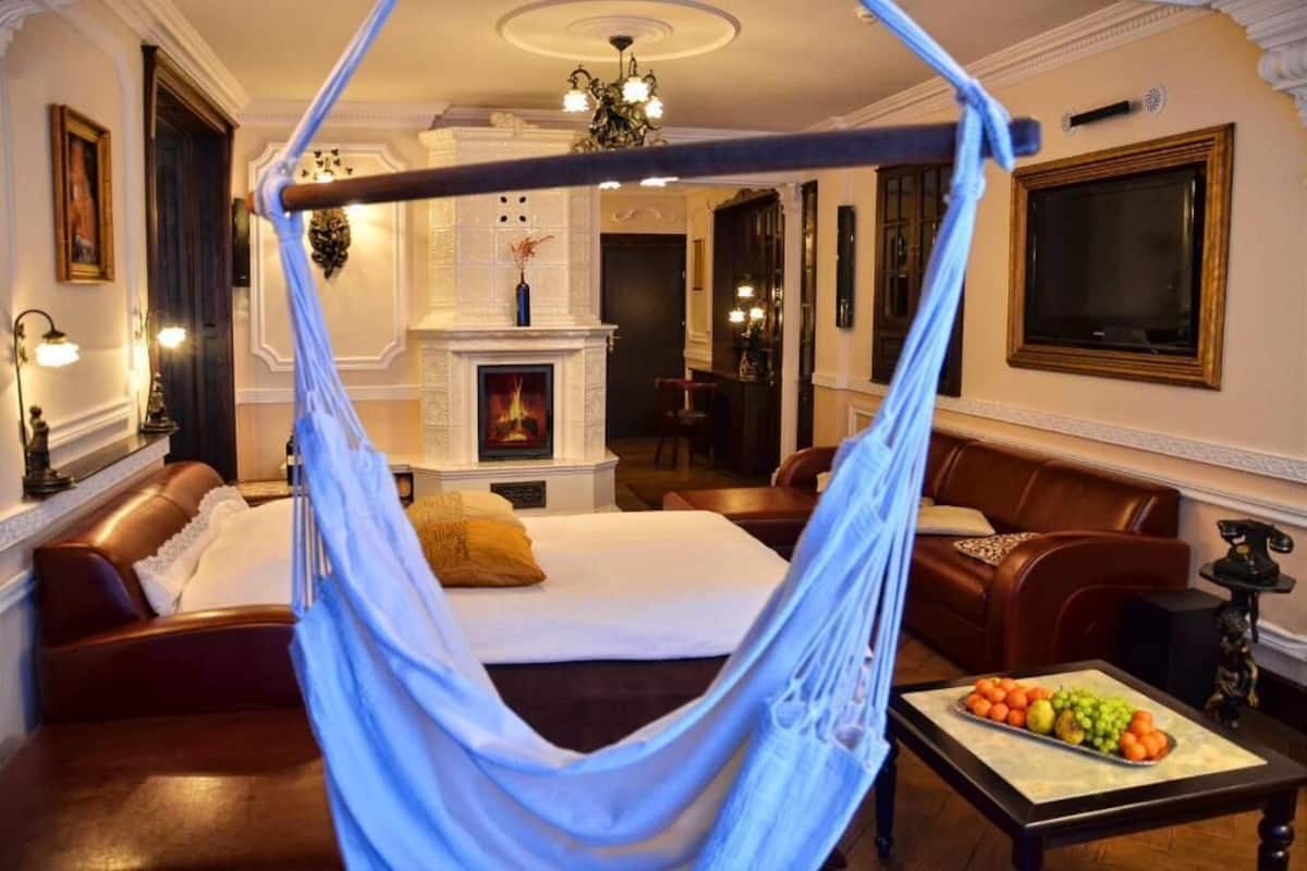 Una habitación con cama con dosel, chimenea, comedor y una mesa de centro con fruta.