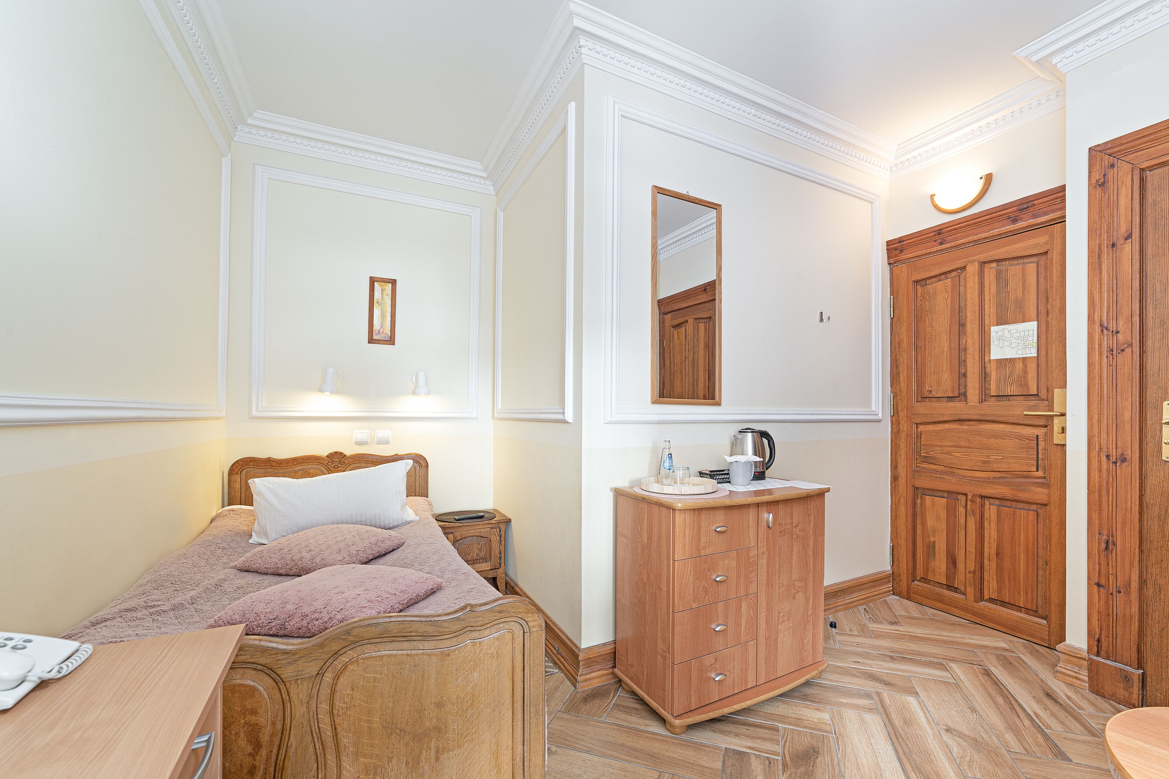 A bedroom with a wooden bed, a wooden dresser, and a large wooden door.