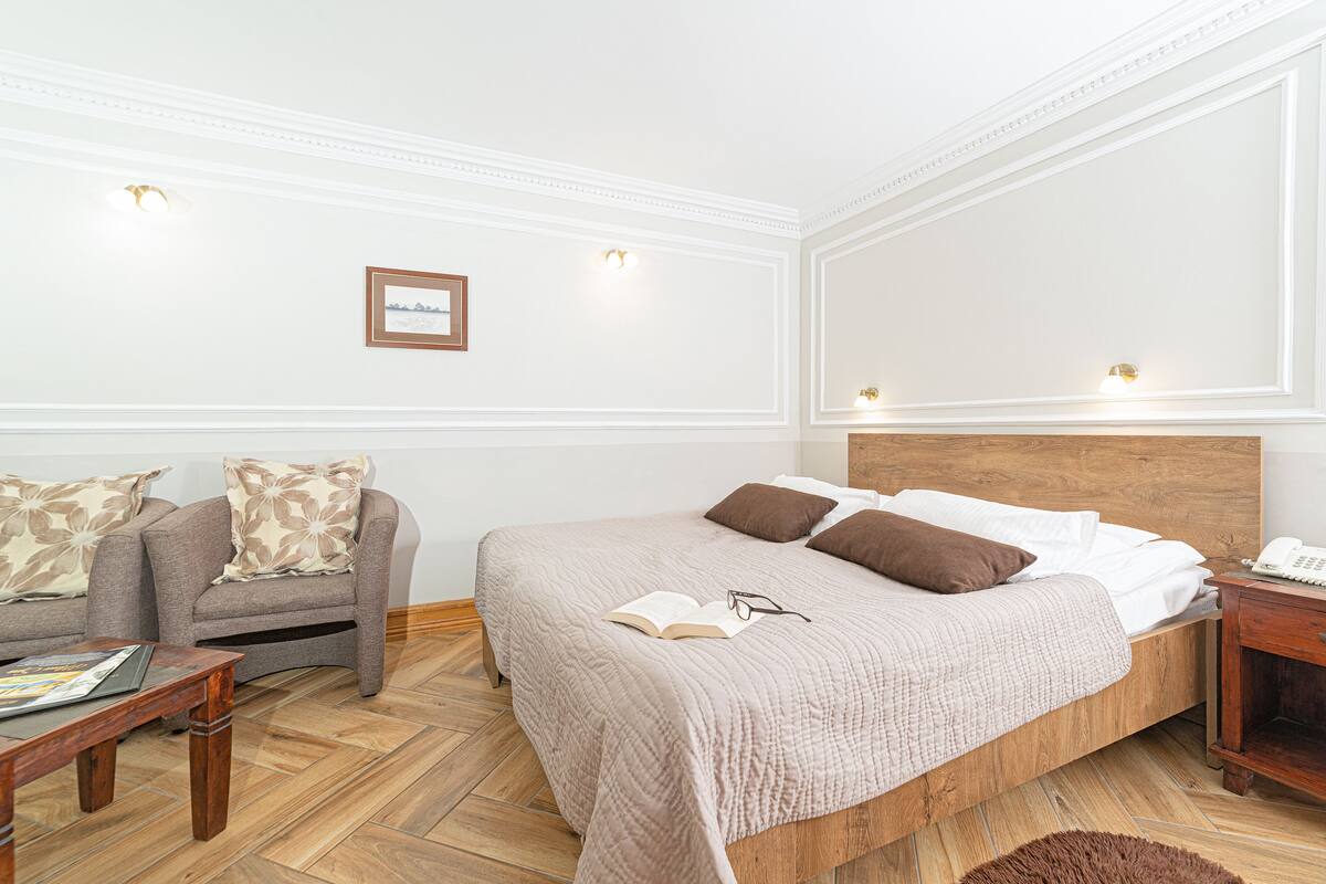 Un dormitorio con cama, sofá, mesita de noche y una mesa de centro de madera.