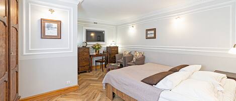 A hotel room with a bed, a desk, a TV, and a wooden wardrobe.