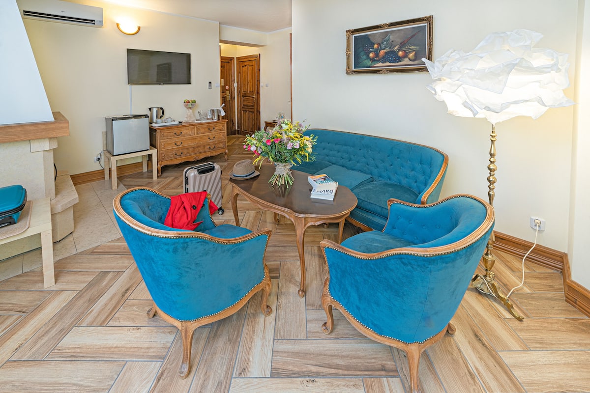 Una sala de estar con un sofá azul, dos sillones a juego, una mesa de centro y una lámpara decorativa.