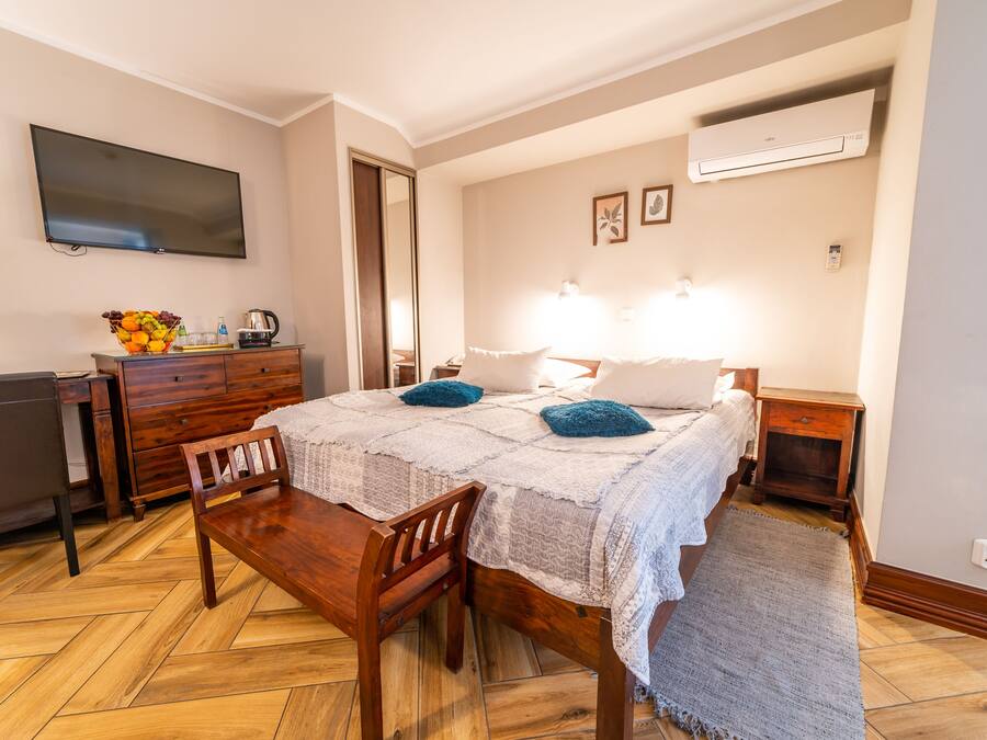 Une chambre à coucher comprenant un lit, des tables de chevet, un bureau, une chaise, une télévision et un panier de fruits.