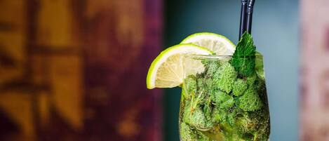 A glass with a lime slice, mint leaves, and a straw.