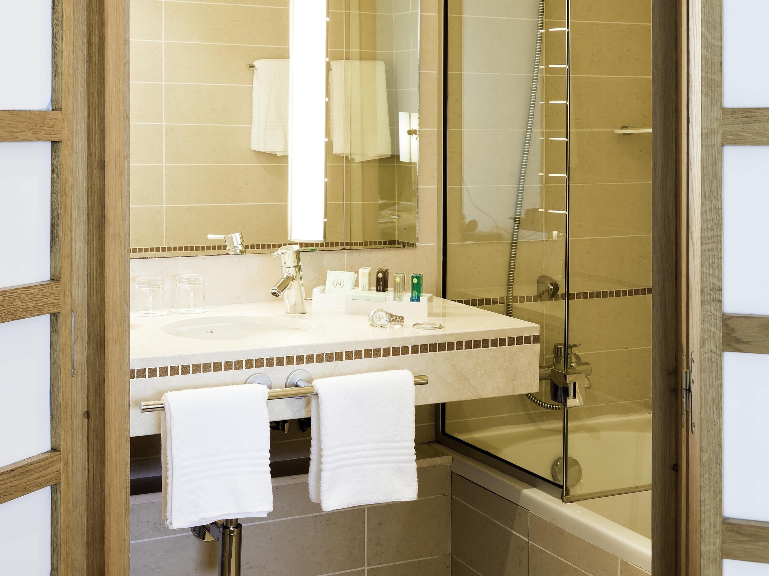 A bathroom with a sink, mirror, and shower.