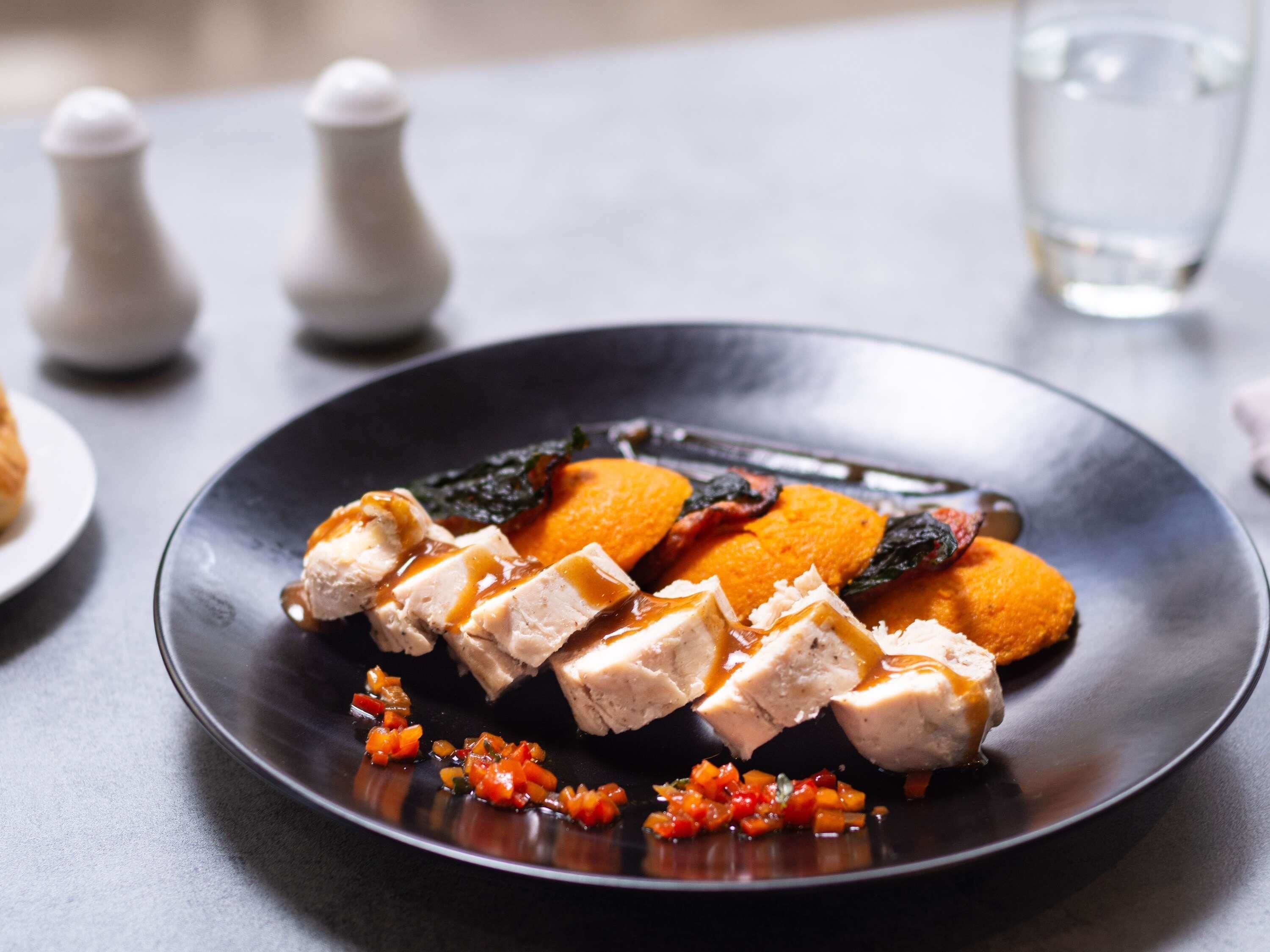 A plate with food, a glass of water, and salt and pepper shakers on a table.