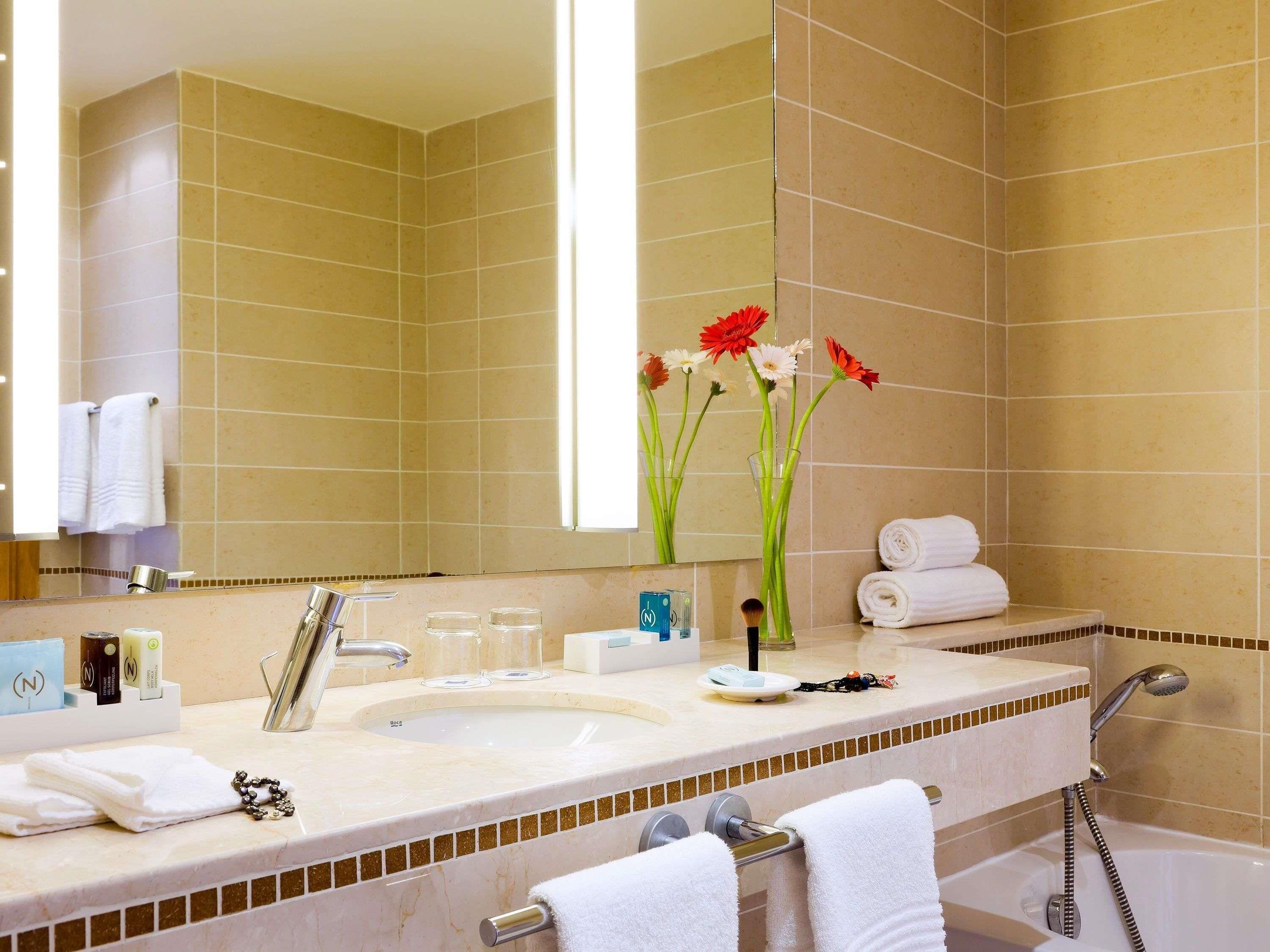 Een badkamer met een wastafel, spiegel, handdoekhouder en douche.