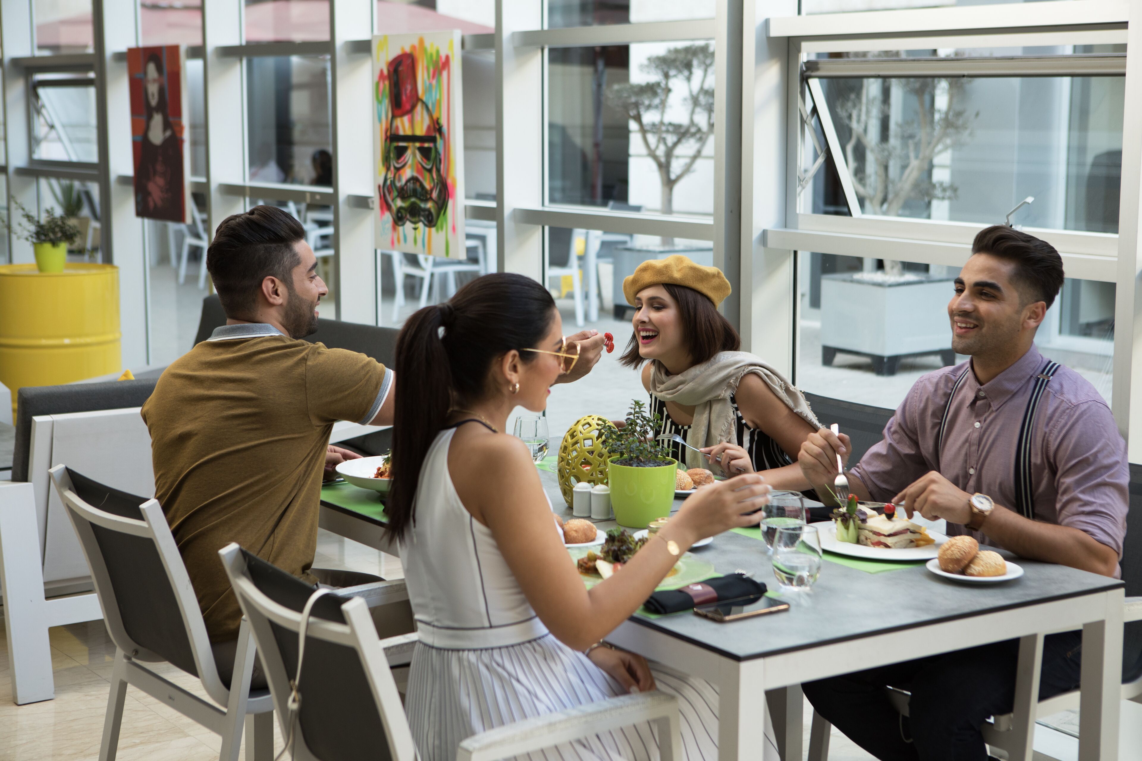 Un grupo de personas cenando en una mesa en un interior moderno, con separadores de vidrio y vistas al exterior.