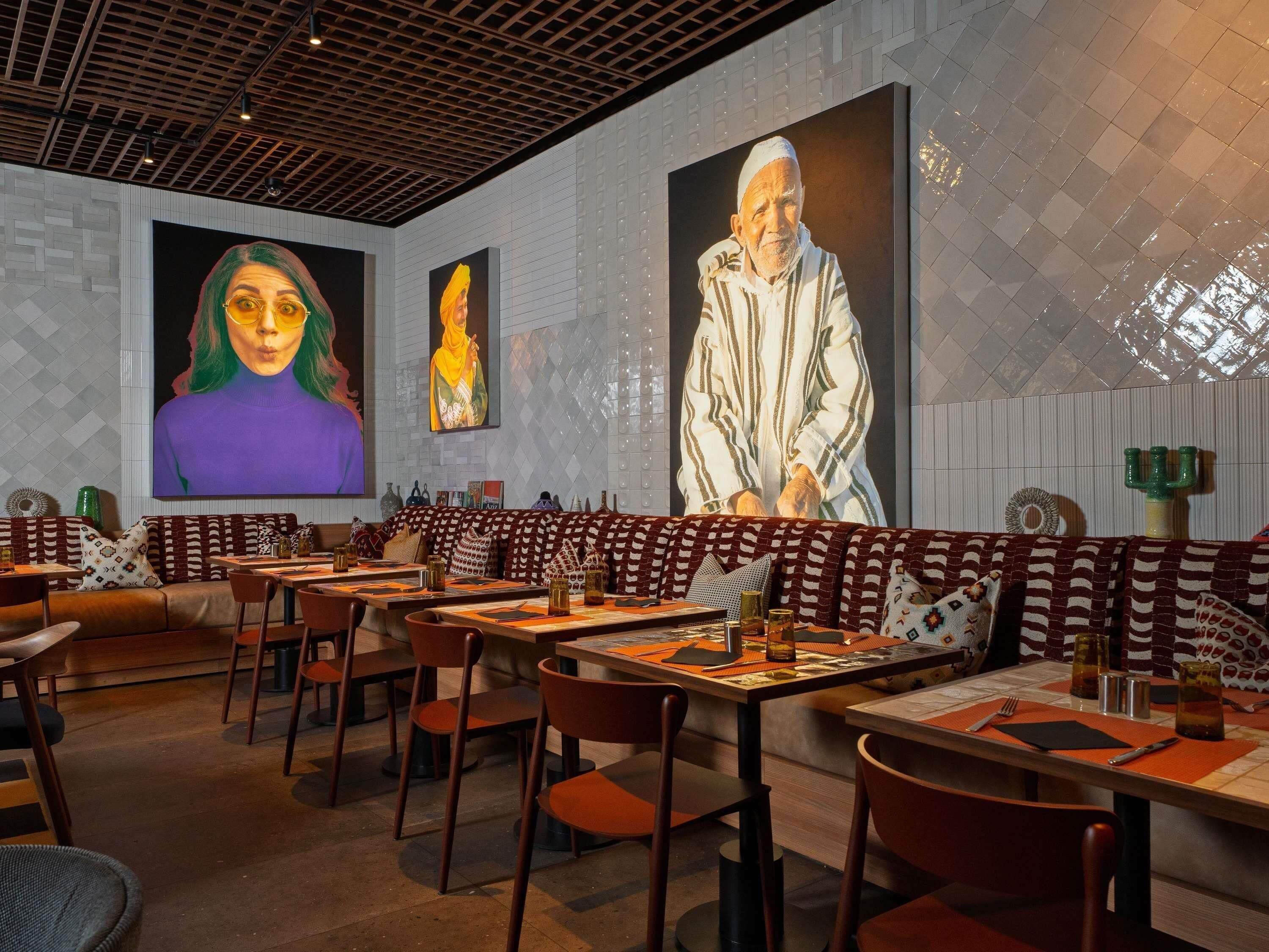 L’intérieur d’un restaurant, avec des banquettes, des tables et un design moderne au niveau du plafond.