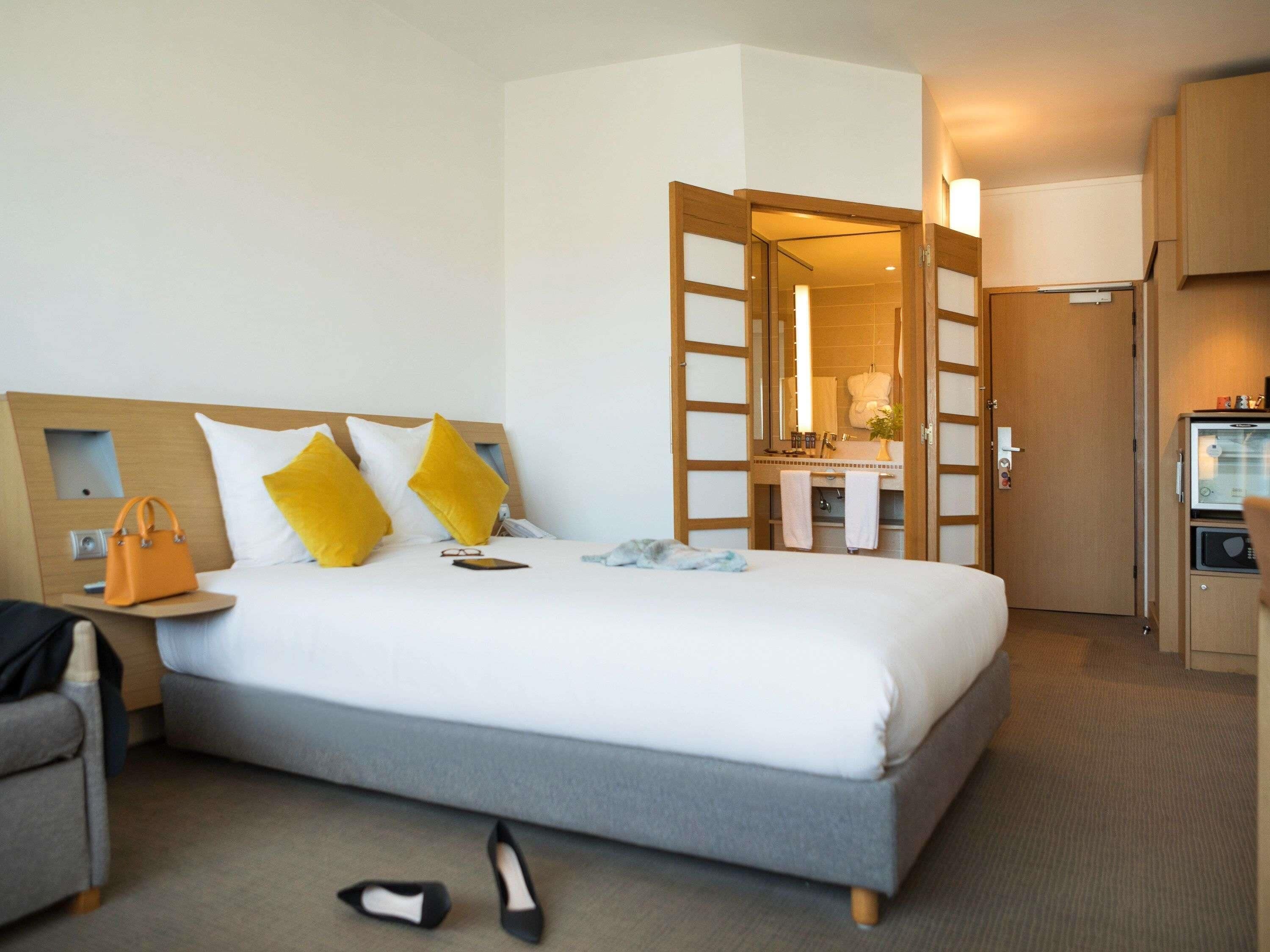A hotel room with a bed, a nightstand, a desk, a chair, and a wardrobe.