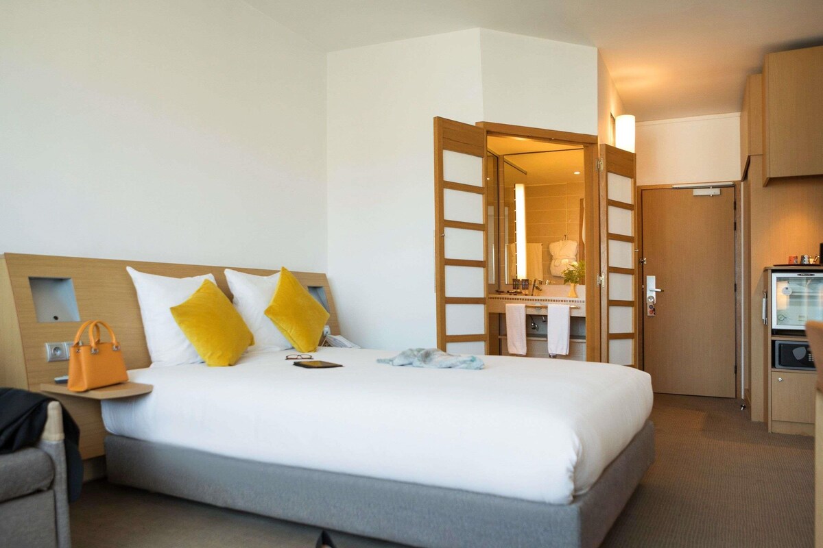 Una habitación de hotel con cama, mesita de noche, escritorio, silla y armario.
