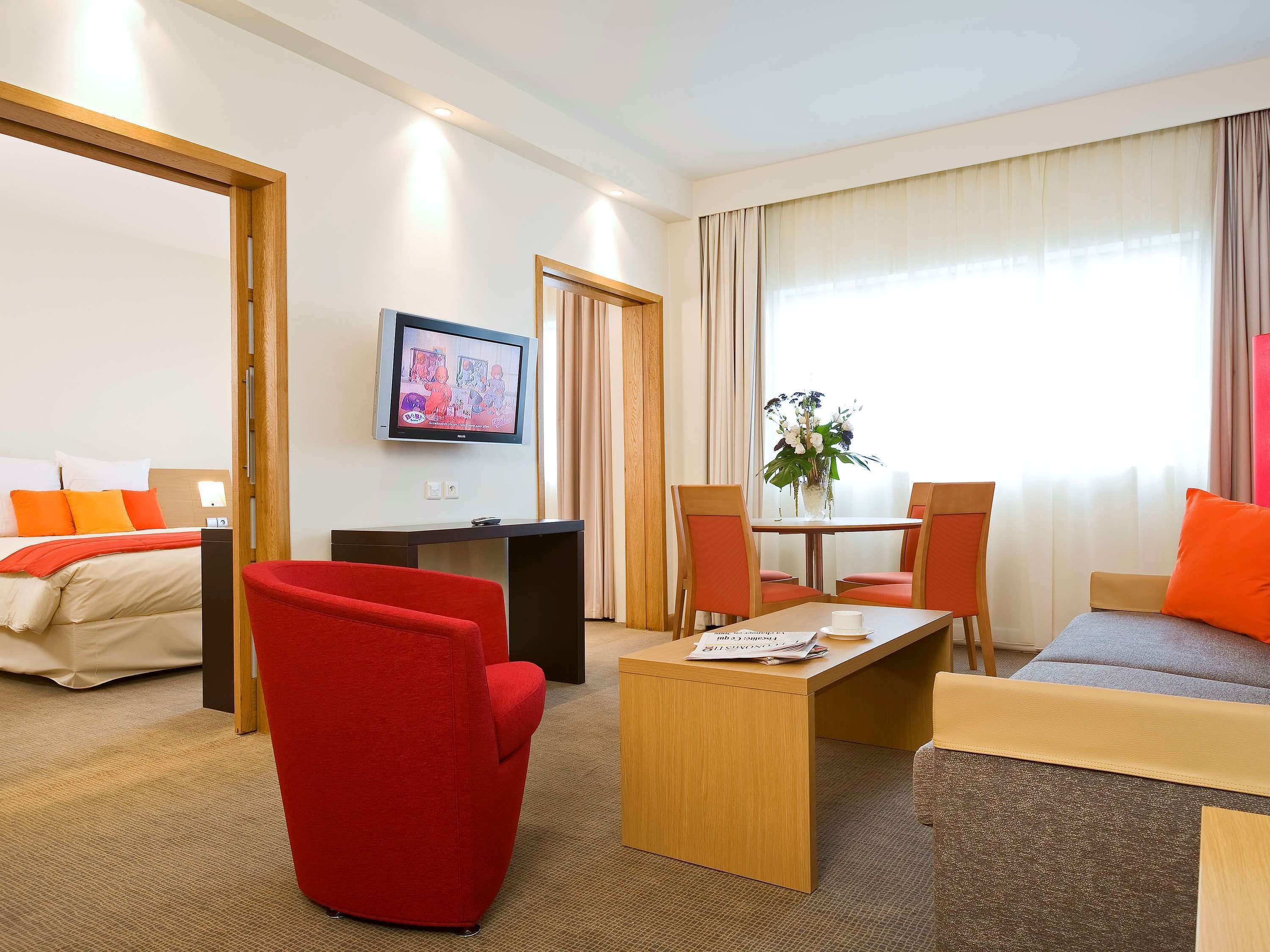 Une chambre d’hôtel comprenant un lit, une télévision, un bureau, une table basse et deux chaises.