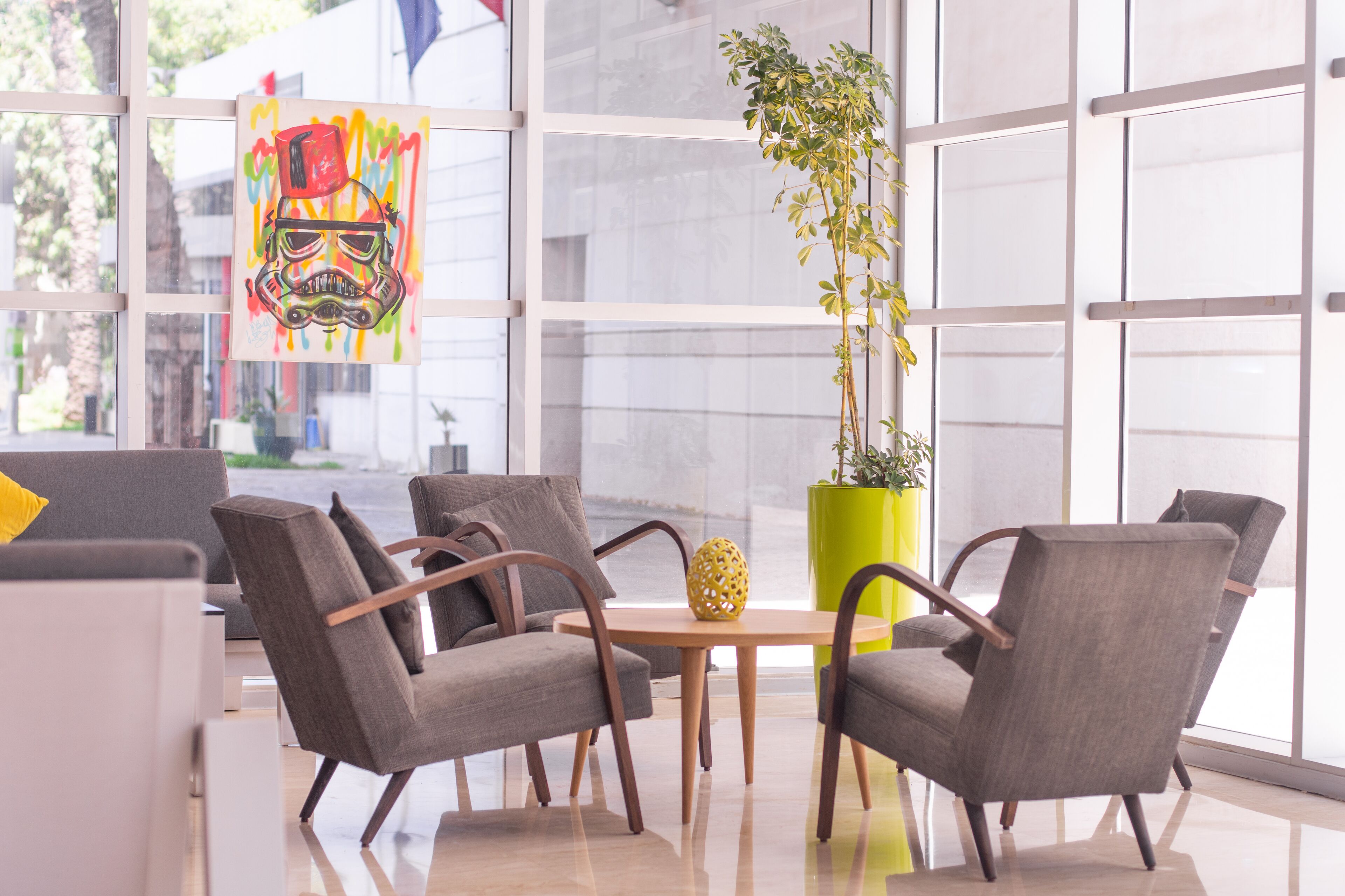 A modern interior with grey upholstered chairs, a wooden table, and a yellow plant.