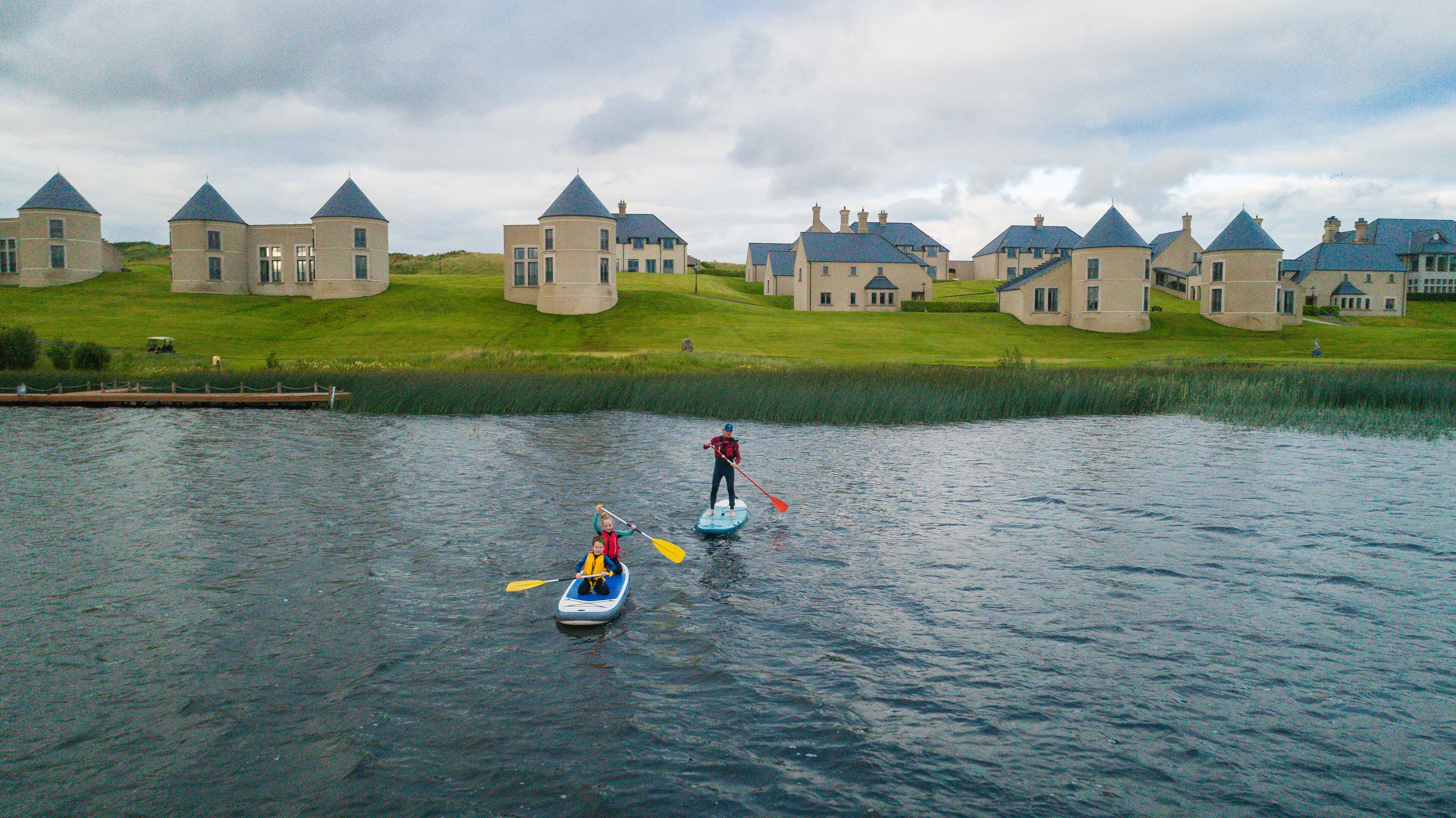 A lake with paddle boats, surrounded by houses with distinctive towers.
