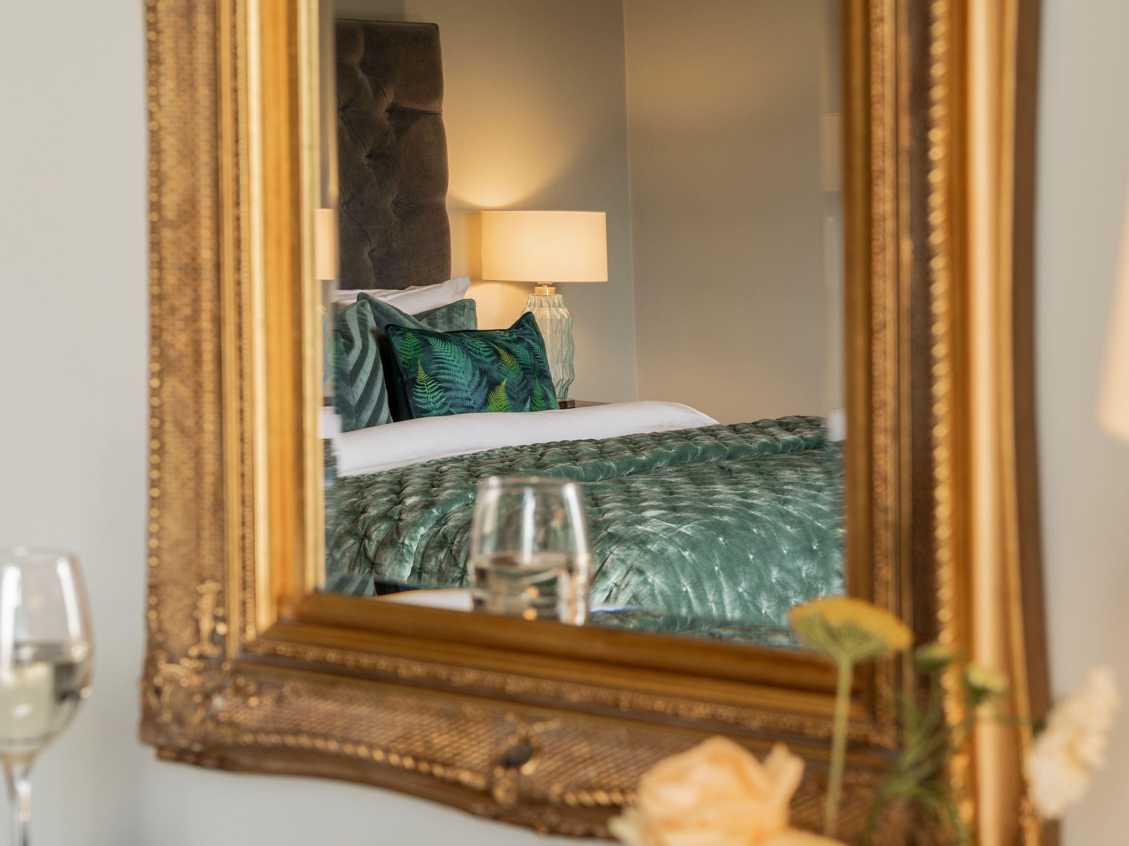A bedroom with a bed, pillows, a bedside table with a lamp, and a glass of water.