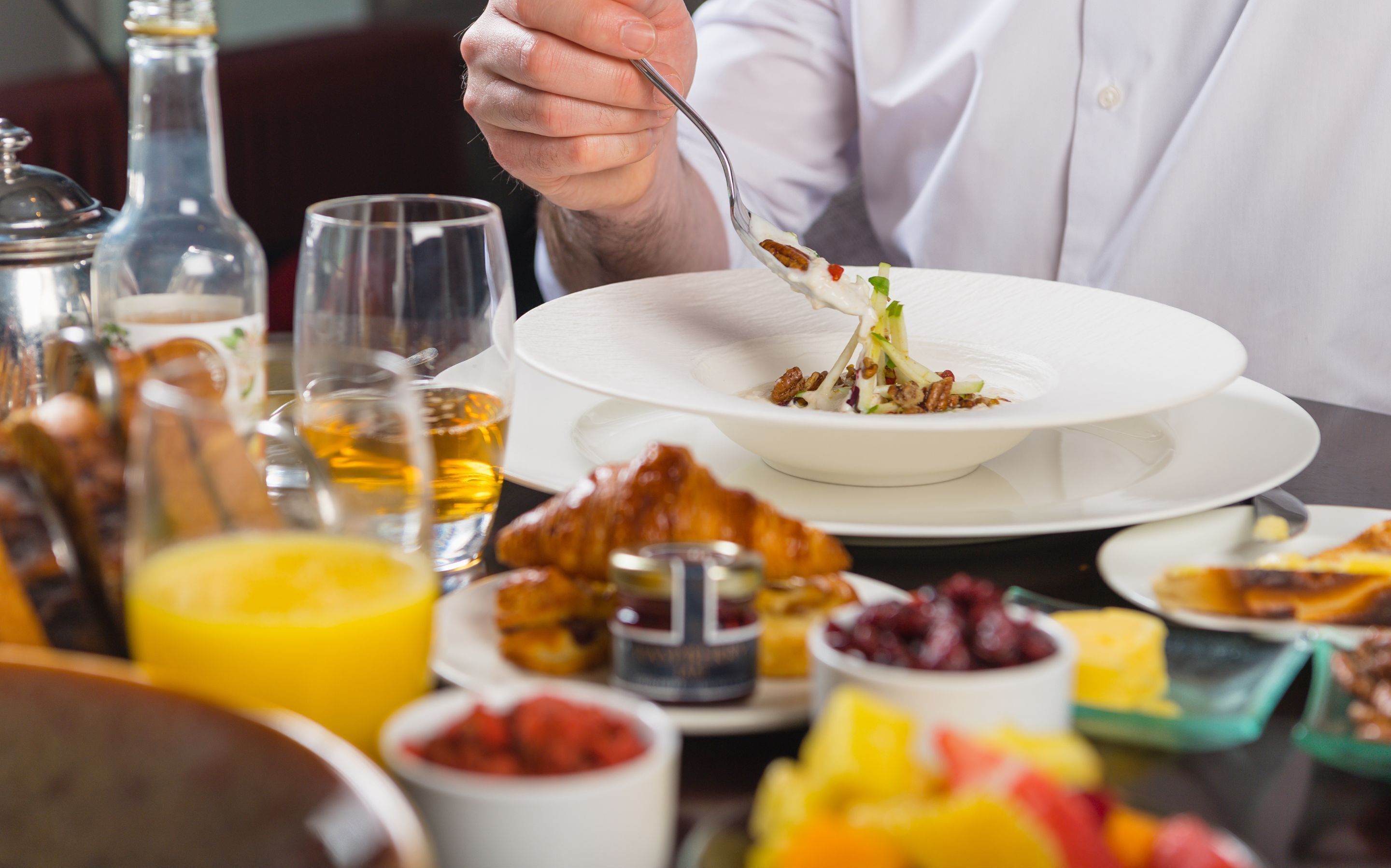 A dining table with various dishes, including a salad, fruit, and condiments.