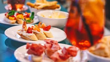 A table with various dishes, including shrimp and tomato-topped bread, and a glass of iced beverage.