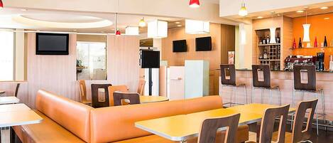 A modern restaurant with booths and tables, a bar area, and a flat-screen TV.