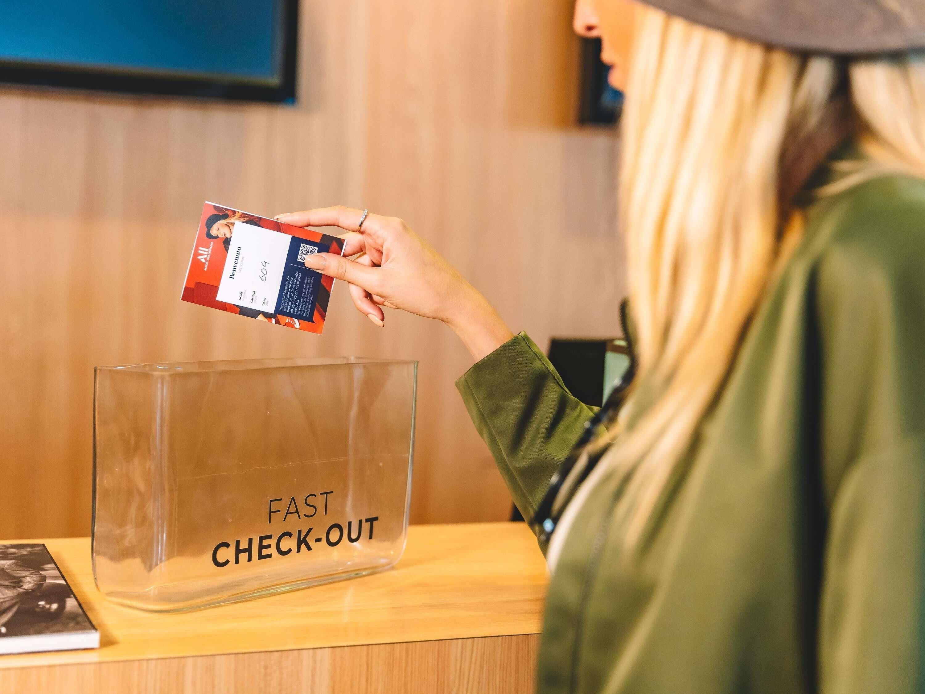 A person using a mobile device at a 'FAST CHECK-OUT' station.