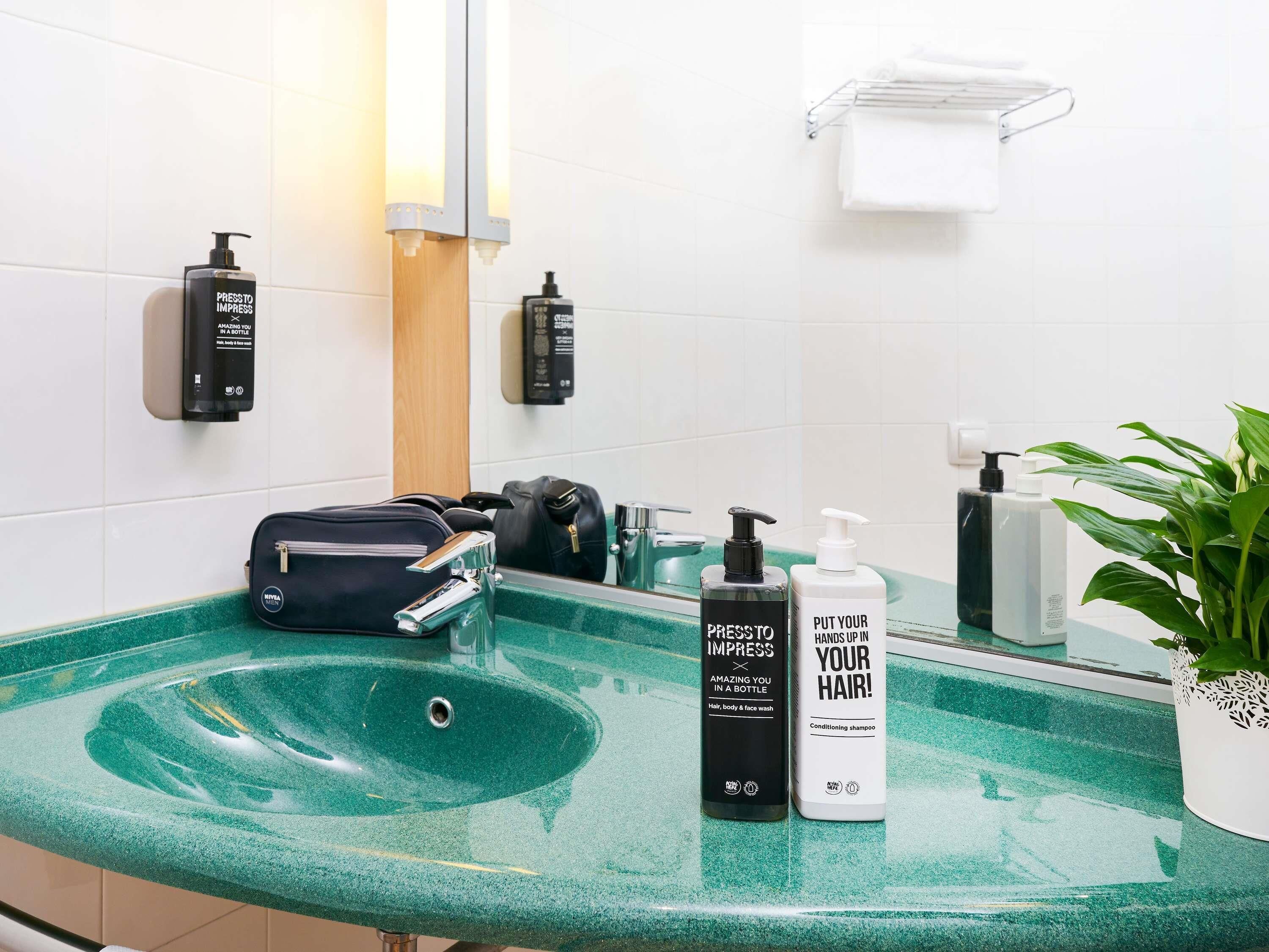 Un baño con lavabo de mármol verde, un espejo, toallero y artículos de aseo.