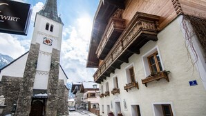 Un pueblo europeo tradicional con una torre de reloj, un cartel que dice 'WIRT Hotel' y edificios con balcones de madera.