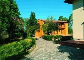 Un camino que lleva a un edificio con fachada amarilla, rodeado de follaje y árboles.