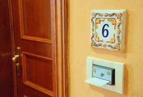 A door with a number plate and a control panel on the wall.