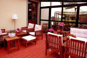 Un'accogliente area patio con mobili in legno, tra cui sedie e un tavolo, e una pianta in vaso.