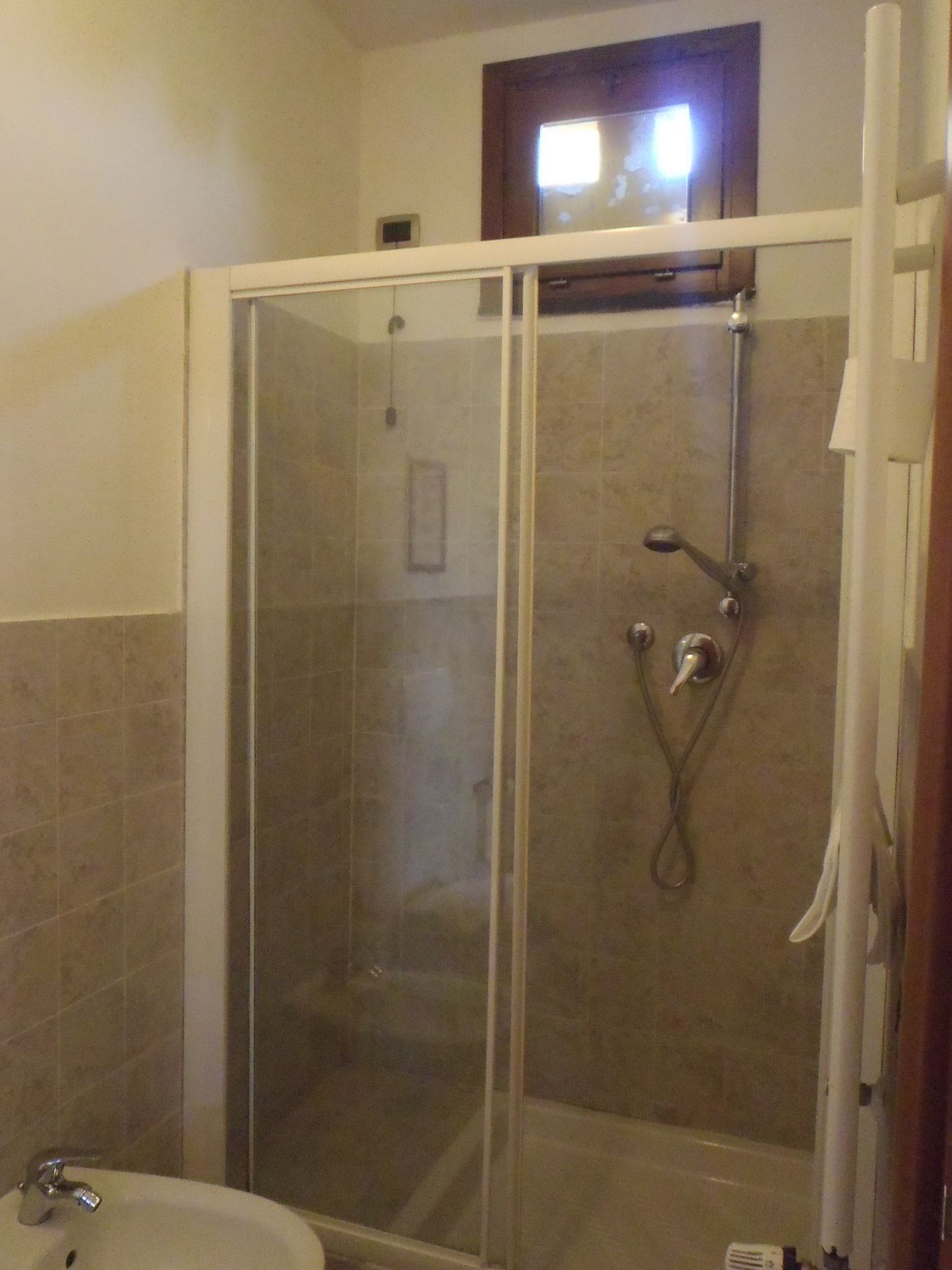 A bathroom with a glass-enclosed shower, a sink, and a toilet.