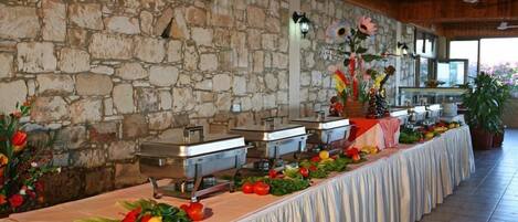 Montaje de bufé con distintos alimentos y un fondo de pared de piedra.