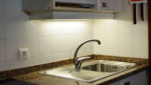 A kitchen with a granite countertop, stainless steel sink, white cabinets, and a microwave. - Cais da Oliveira (Santa Cruz)