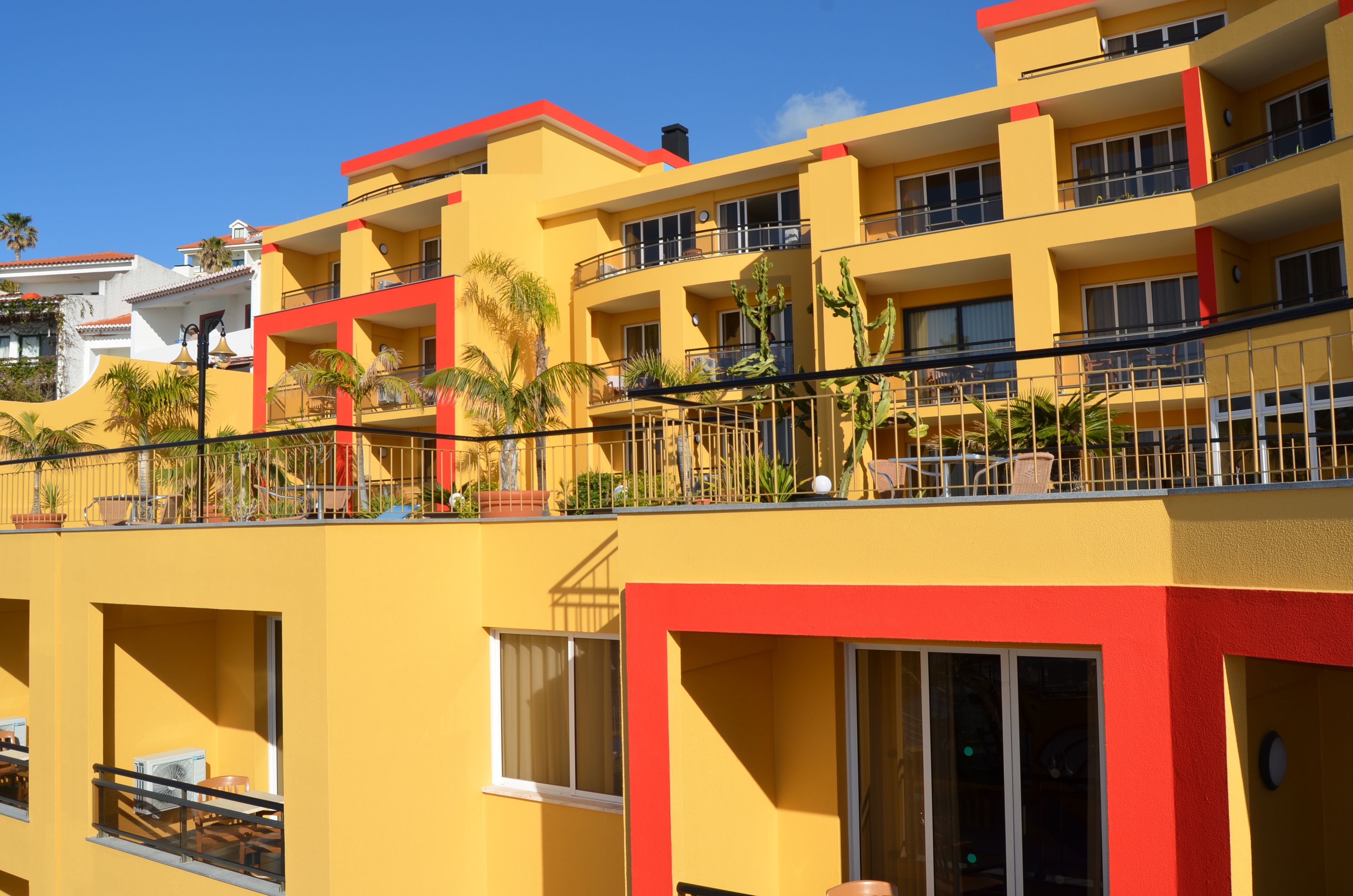 Un hôtel à plusieurs étages doté de balcons, de climatiseurs et de mobilier d’extérieur.