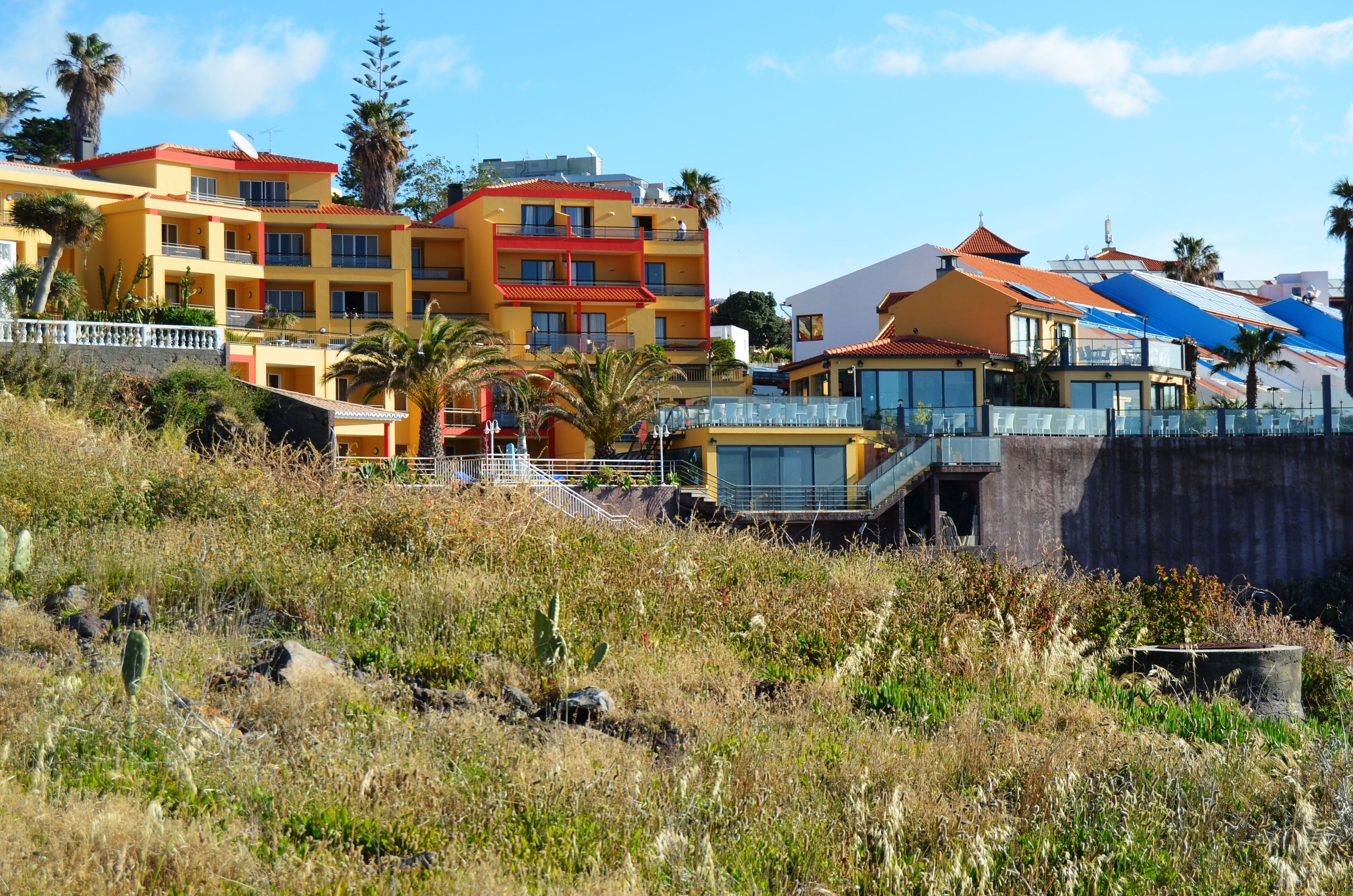 A coastal hotel with multiple floors, balconies, and a pool area.
