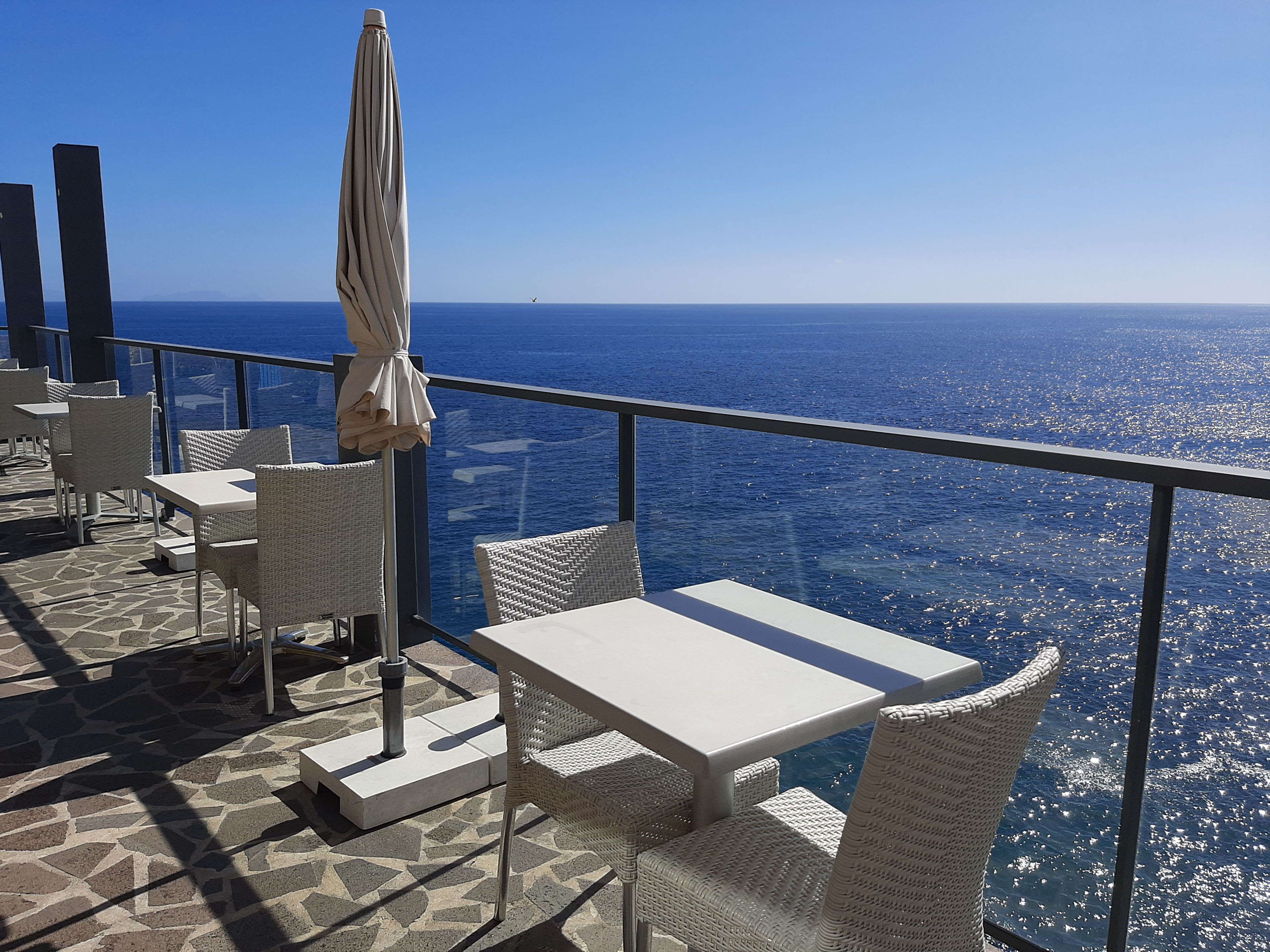 A terrace with tables and chairs overlooking a body of water.