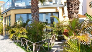 A modern building with large windows, a stone pathway, and tropical plants. - Cais da Oliveira (Santa Cruz)