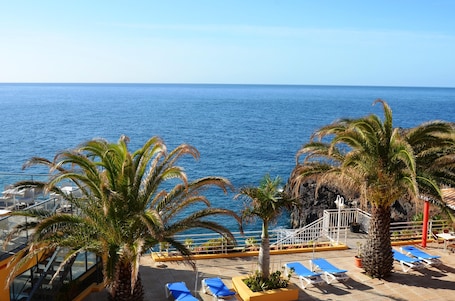 Una piscina techada, una piscina al aire libre, sombrillas