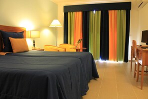 A hotel room with two beds, a desk, a chair, a lamp, and a television. - Cais da Oliveira (Santa Cruz)
