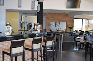 Une cuisine moderne avec un mur d’accent en briques, un coin bar avec des tabourets et une grande fenêtre qui laisse entrer la lumière naturelle.