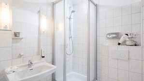 A modern bathroom with a glass-enclosed shower, a sink, and a towel rack. - AKZENT Hotel Dorn (Büsum)