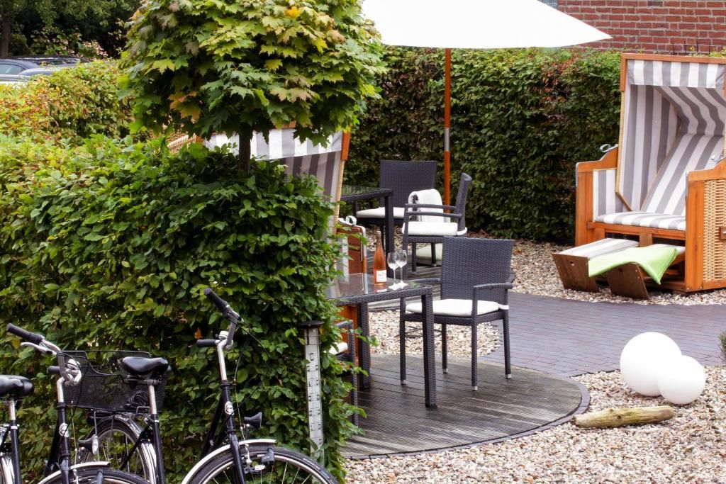 An outdoor seating area with wicker furniture, a bicycle, and a hedge.
