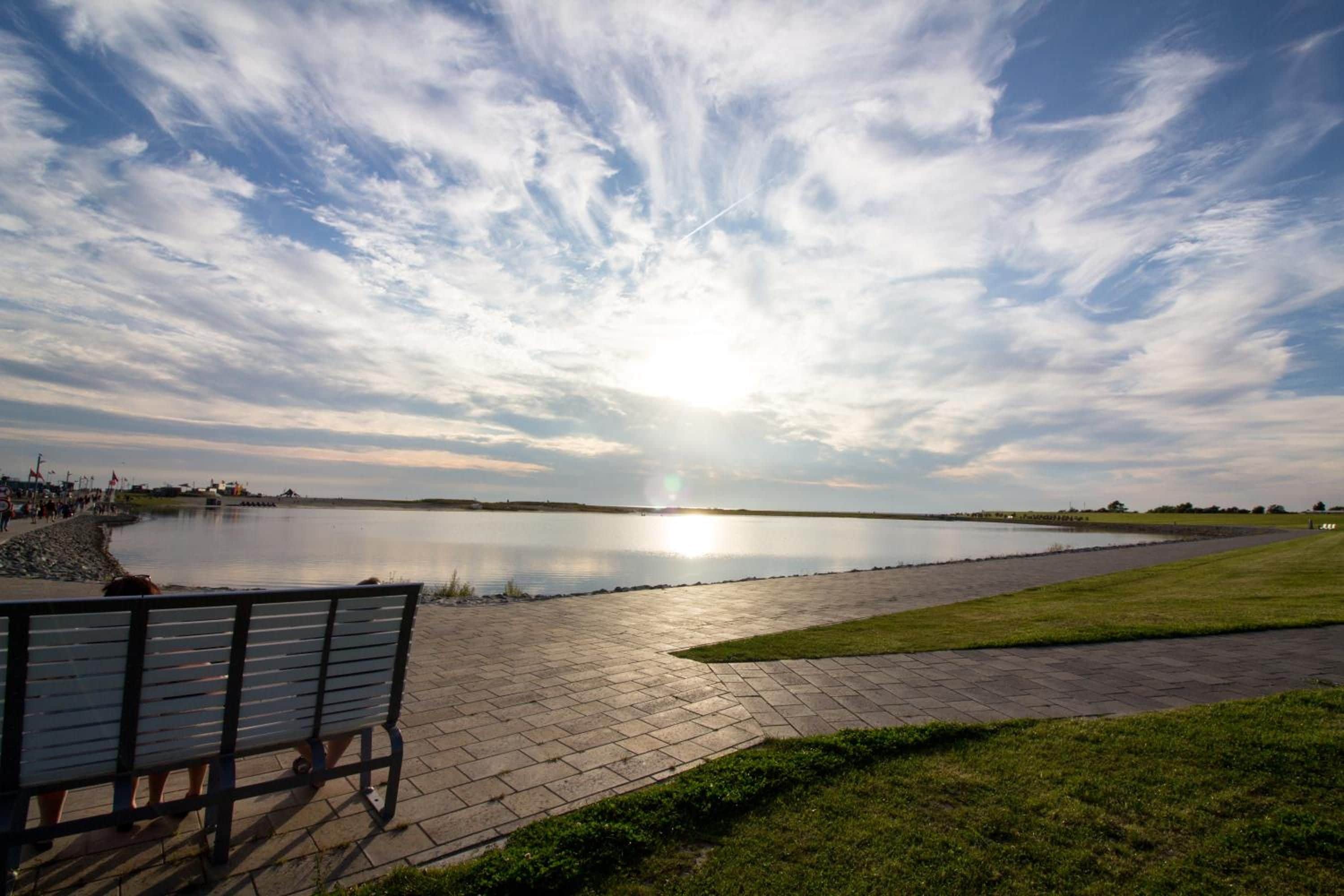 A bench overlooking a calm body of water with a clear sky.