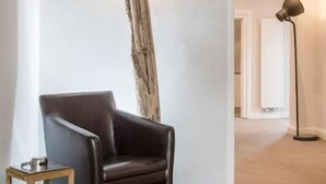A room with a dark leather chair, a tall wooden sculpture, and a floor lamp. - AKZENT Hotel Dorn (Büsum)