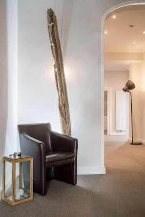 A room with a dark leather chair, a tall wooden sculpture, and a floor lamp. - AKZENT Hotel Dorn (Büsum)